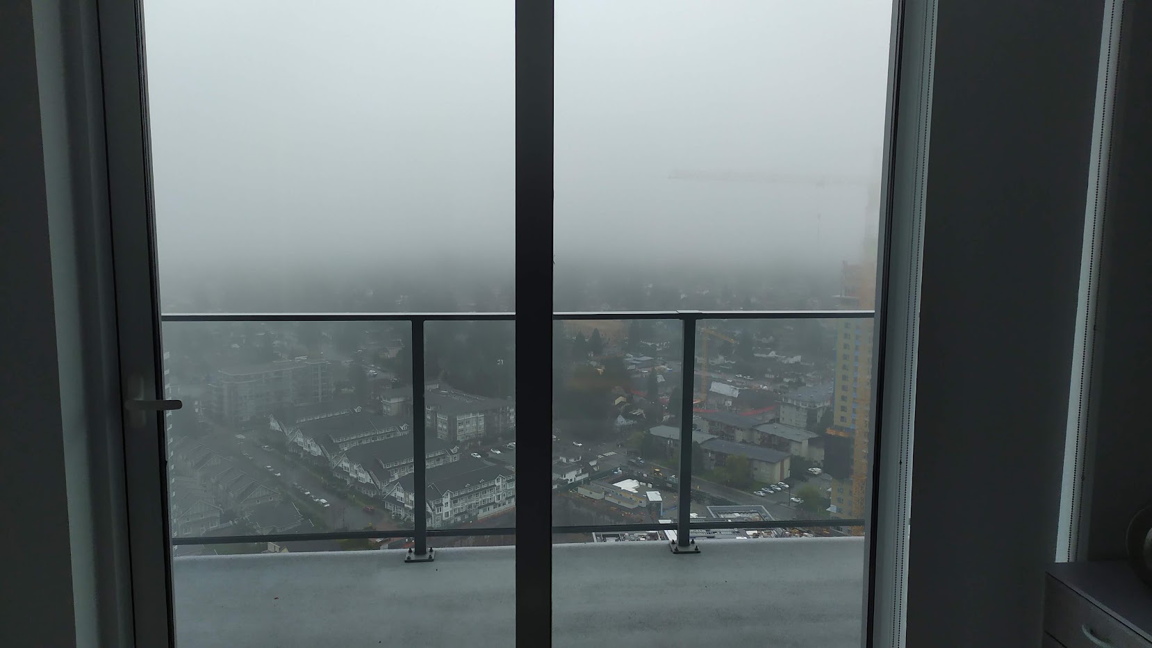 Dreary view of a foggy city through a highrise balcony.